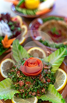 Multiple lebanese appetizers and salads together on the table. focused on tabbouleh