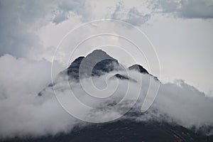 Multiple mountain peaks poking through clouds