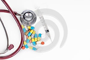 Multiple pills, tablet, caplet, capsule with stethoscope, and syringe. Healthcare concept