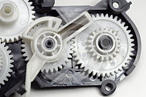 Multiple reducer gears of white plastic, spring and black case - parts of inkjet printer paper feeder mechanical drive