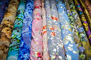 Multiple rolls of fabric in a marketplace with flower prints