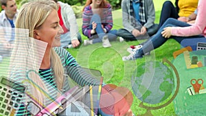 Multiple school icons against portrait of caucasian female college student smiling sitting on grass