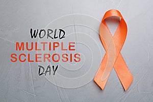 Multiple Sclerosis Awareness Day. Orange ribbon on light grey background, top view