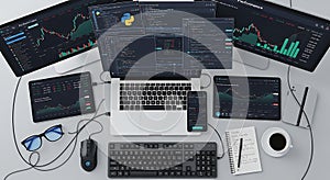 Multiple screens displaying financial trading charts and programming code on a desk