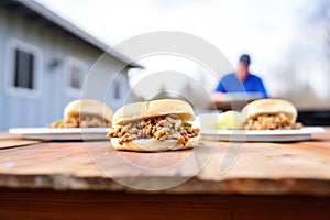 multiple sloppy joes on a picnic table, outdoor light