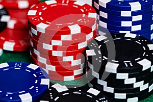 Multiple stacks of Red, Blue and Black Clay casino style betting chips on a green felt gaming surface.  Room for Copy