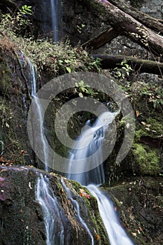 Multiple streams of water cascading over moss covered rocks in a mountain landscape