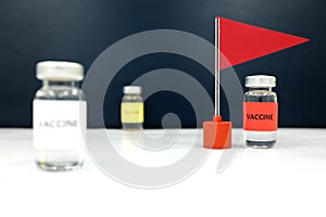 Multiple vaccine vials and a red flag. Coronavirus covid-19 vaccine candidate development race and competition winner concept.