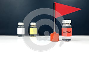 Multiple vaccine vials and a red flag. Coronavirus covid-19 vaccine candidate development race and competition winner concept.