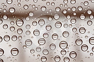 Multiple water drops or raindrops of different sizes on a window glass