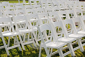 Multiple white folding chairs for event. Outdoor city wedding