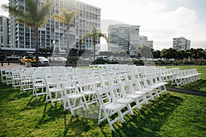 Multiple white folding chairs for event. Outdoor city wedding