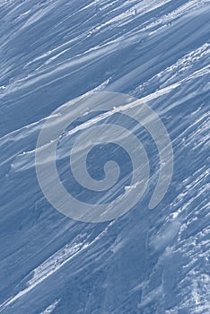 Multiple wind packed snow ridges forming oblique lines in sunshine