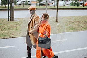 A multiracial business couple in stylish outfits walk side by side on a cloudy day, engaged in a pleasant conversation