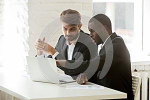 Multiracial business partners in suits discussing online project