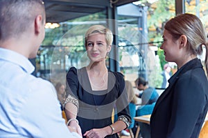 Multiracial business people working connected with technological devices at the bar. Group of three young creative coworkers