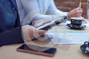 Multiracial business people working connected with technological devices at the bar. Group of three young creative coworkers