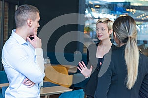 Multiracial business people working connected with technological devices at the bar. Group of three young creative coworkers