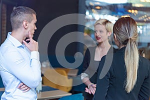 Multiracial business people working connected with technological devices at the bar. Group of three young creative coworkers