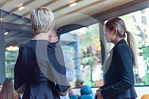 Multiracial business people working connected with technological devices at the bar. Group of three young creative coworkers