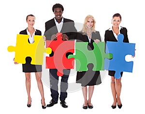 Multiracial businesspeople holding jigsaw puzzle