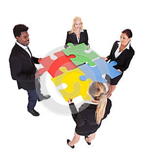 Multiracial businesspeople holding jigsaw puzzle