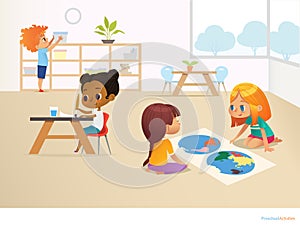 Multiracial children in Montessori classroom. Girls viewing world map