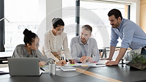 Multiracial colleagues discuss company paperwork in meeting