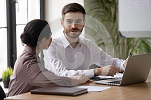 Multiracial colleagues work on laptop discussing ideas