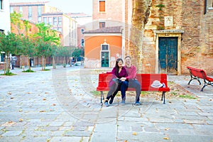 Multiracial couple in early fifties on red bench in Italy