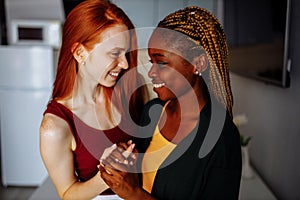 Multiracial couple girlfriends in love embracing in room