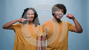 Multiracial couple Hispanic woman girl and Indian man Arabian guy holding tooth brush pretend brushing teeth dental care