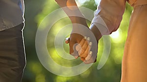 Multiracial couple holding hands at sunny park, romantic and intimacy, close-up