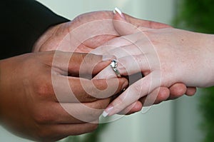 Multiracial couple placing wedding ring on finger