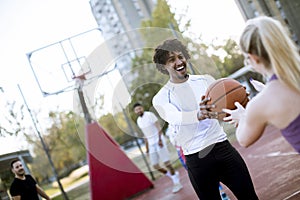 Multiracial couple playing basketball on outdoor court at outumn day