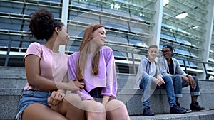 Multiracial couples of teenagers sitting stairs outdoor, romantic youth, leisure