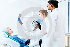 Multiracial dental team checking teeth x ray of patient. Dental clinic concept.