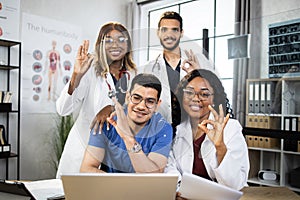 Multiracial doctors showing okay approval sign at office meeting