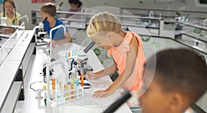 Multiracial elementary students looking through microscope during science class