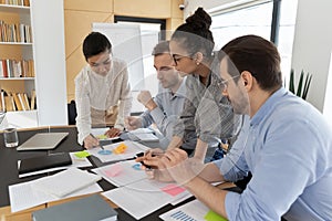 Multiracial employees brainstorm discussing paperwork at meeting