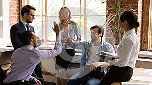 Multiracial employees giving high five during group briefing in office