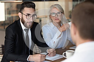 Multiracial employers talk with male applicant at interview