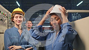 Multiracial engineers team take off hard hats with smiles in industry factory.