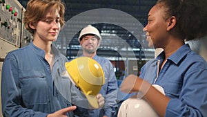 Multiracial engineers team take off hard hats with smiles in industry factory.