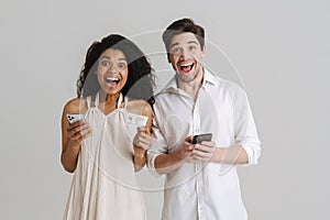 Multiracial excited man and woman posing with cellphones and credit card