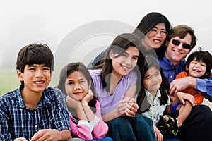 Multiracial family of seven sitting on beach