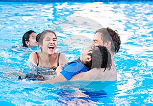 Multiracial family swimming together in pool. Disabled youngest