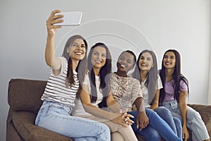 Multiracial female best friends take selfies together and capture moment with mobile phone camera.