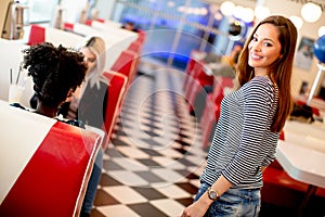 Multiracial female friends eating fast food at a table in the di