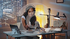 Multiracial female journalist doing online interview on the computer in home recording studio